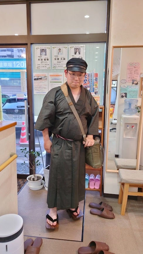 Person wearing dark Japanese traditional-style clothing with geta sandals