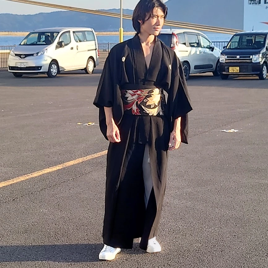 Person wearing black Japanese-style clothing with an obi outdoors